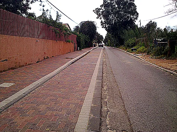 כביש עם שביל אופניים אדום ומדרכה מרוצפת לאורכו